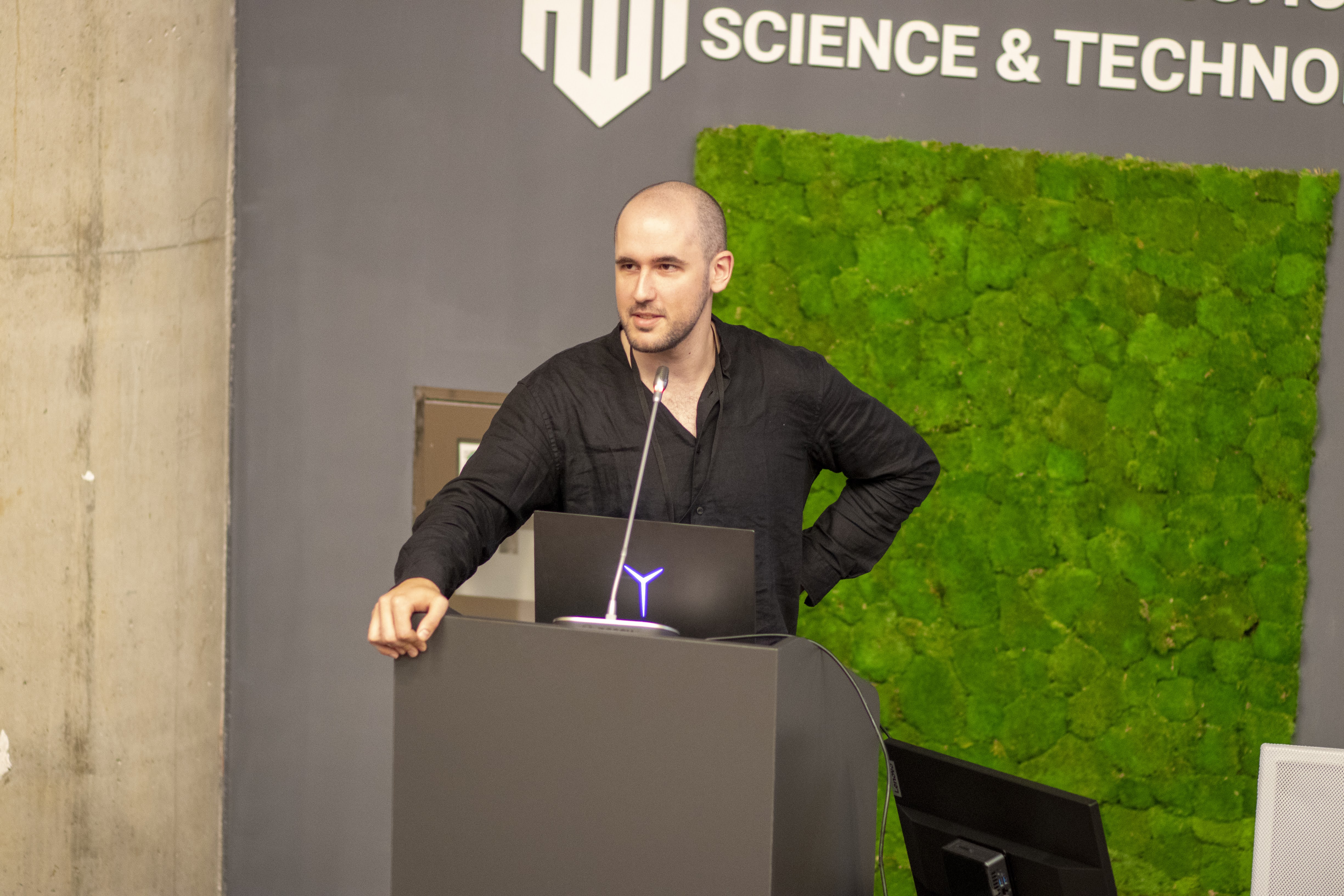 The author standing at a podium giving a reinforcement learning lecture at EEML 2024.